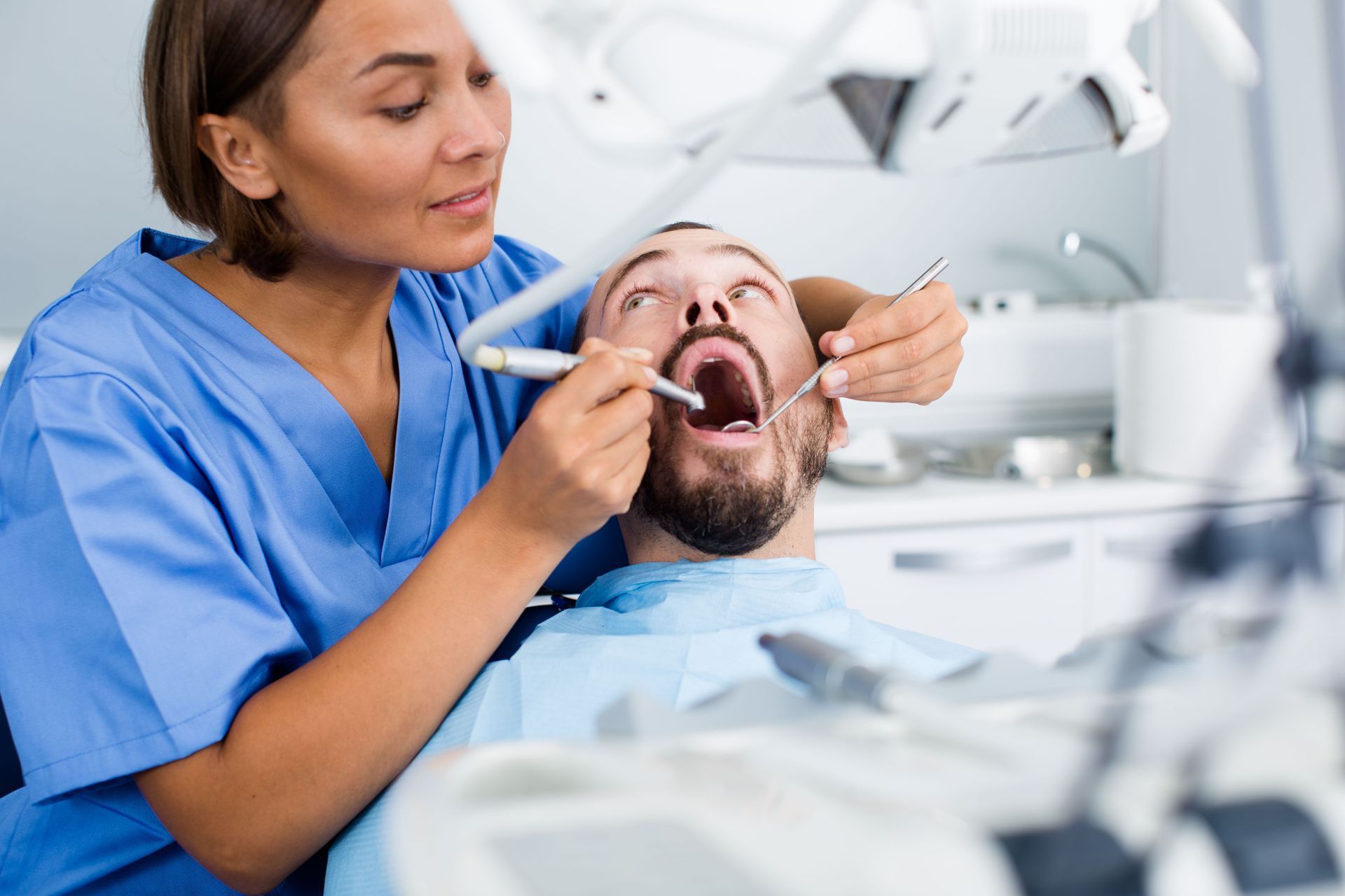 Dentist examining a patient’s open mouth in a bright dental clinic