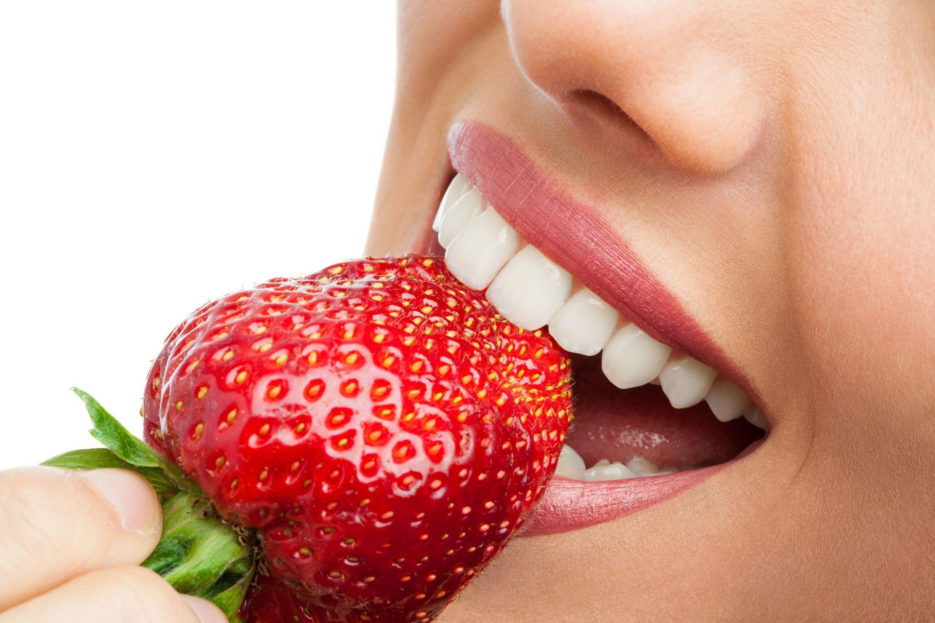 A person biting a ripe red strawberry held near their mouth