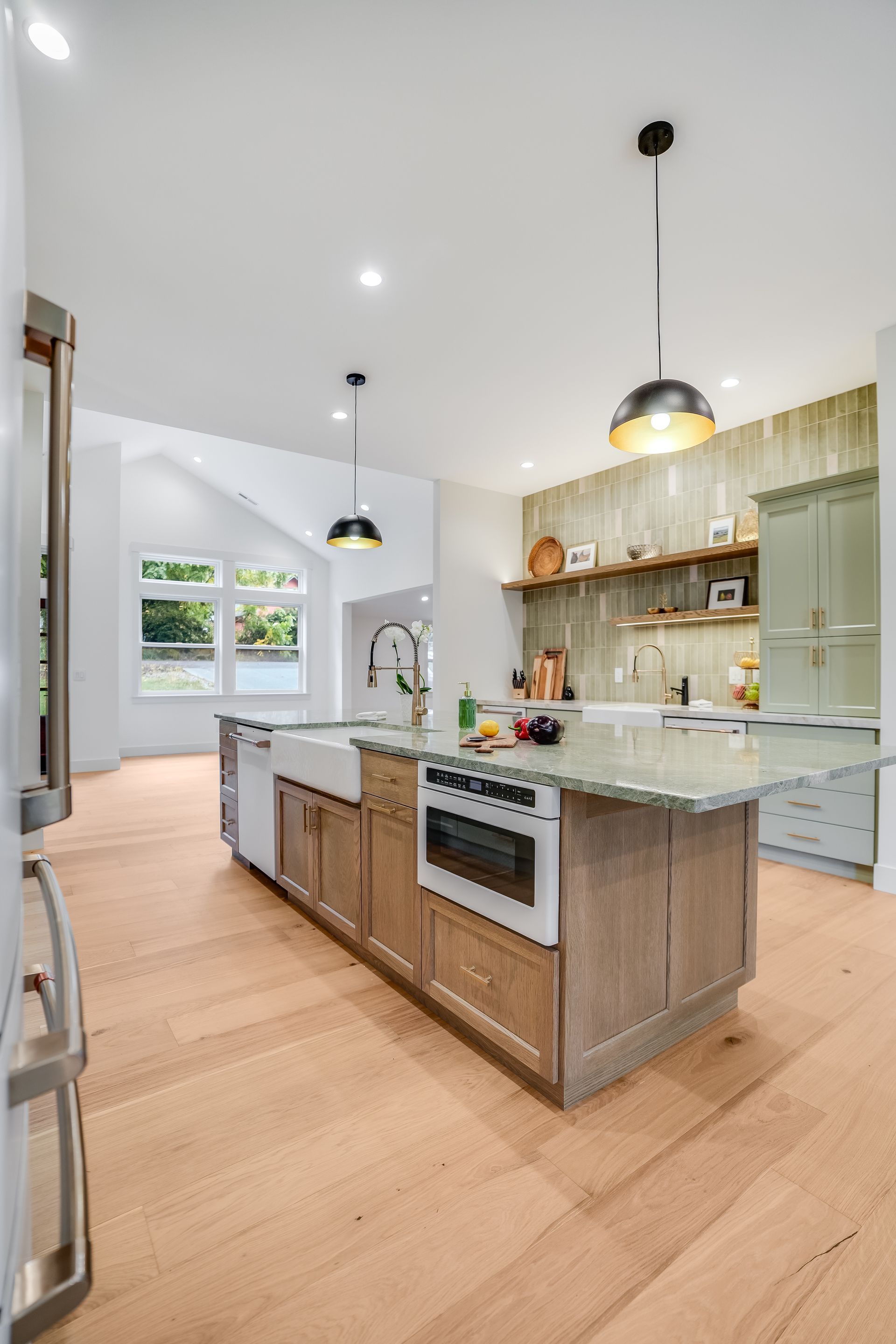 Modern kitchen with a wooden island, light wood floors, and green cabinetry.