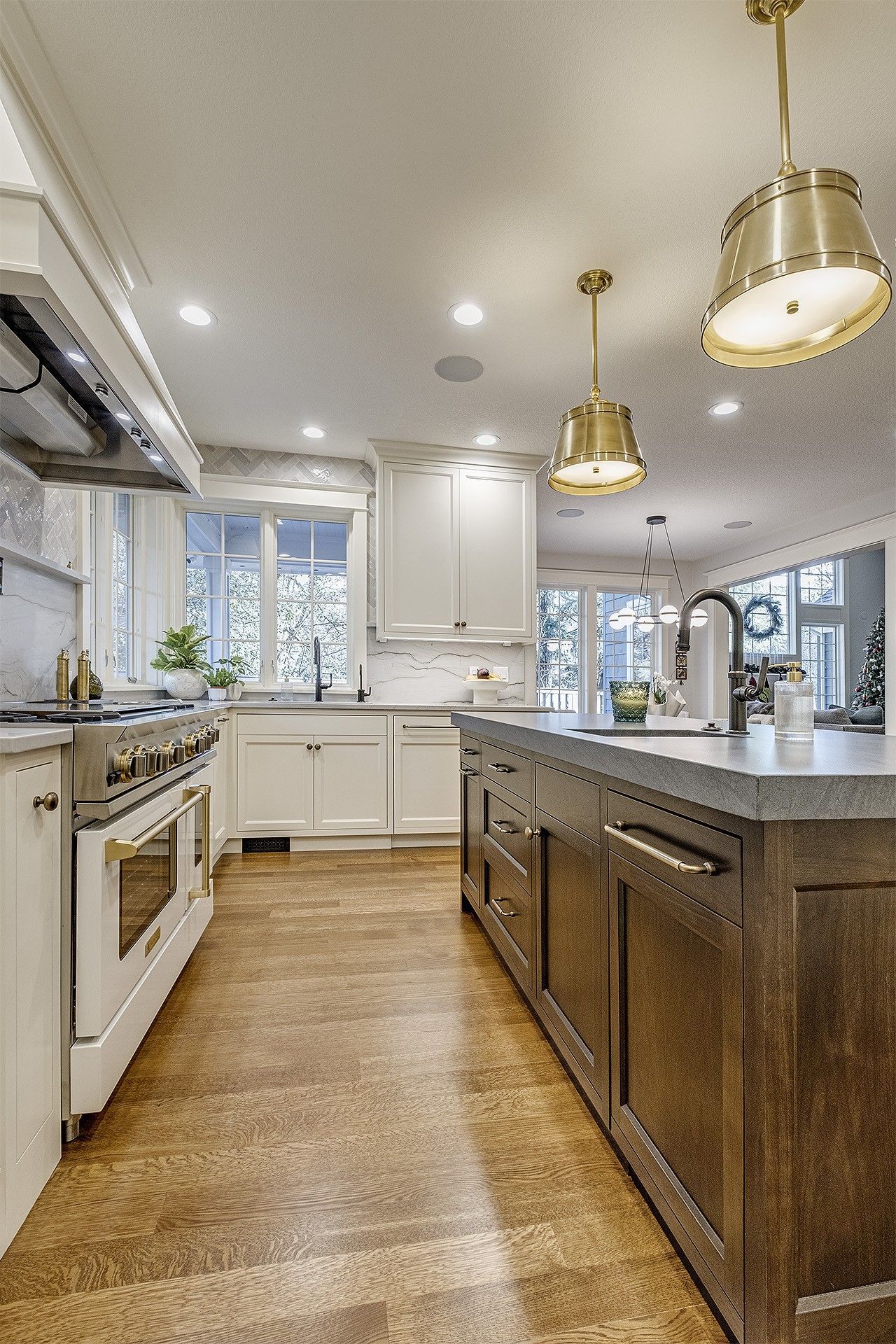 A kitchen with white cabinets, a large island, a stove, and a sink.