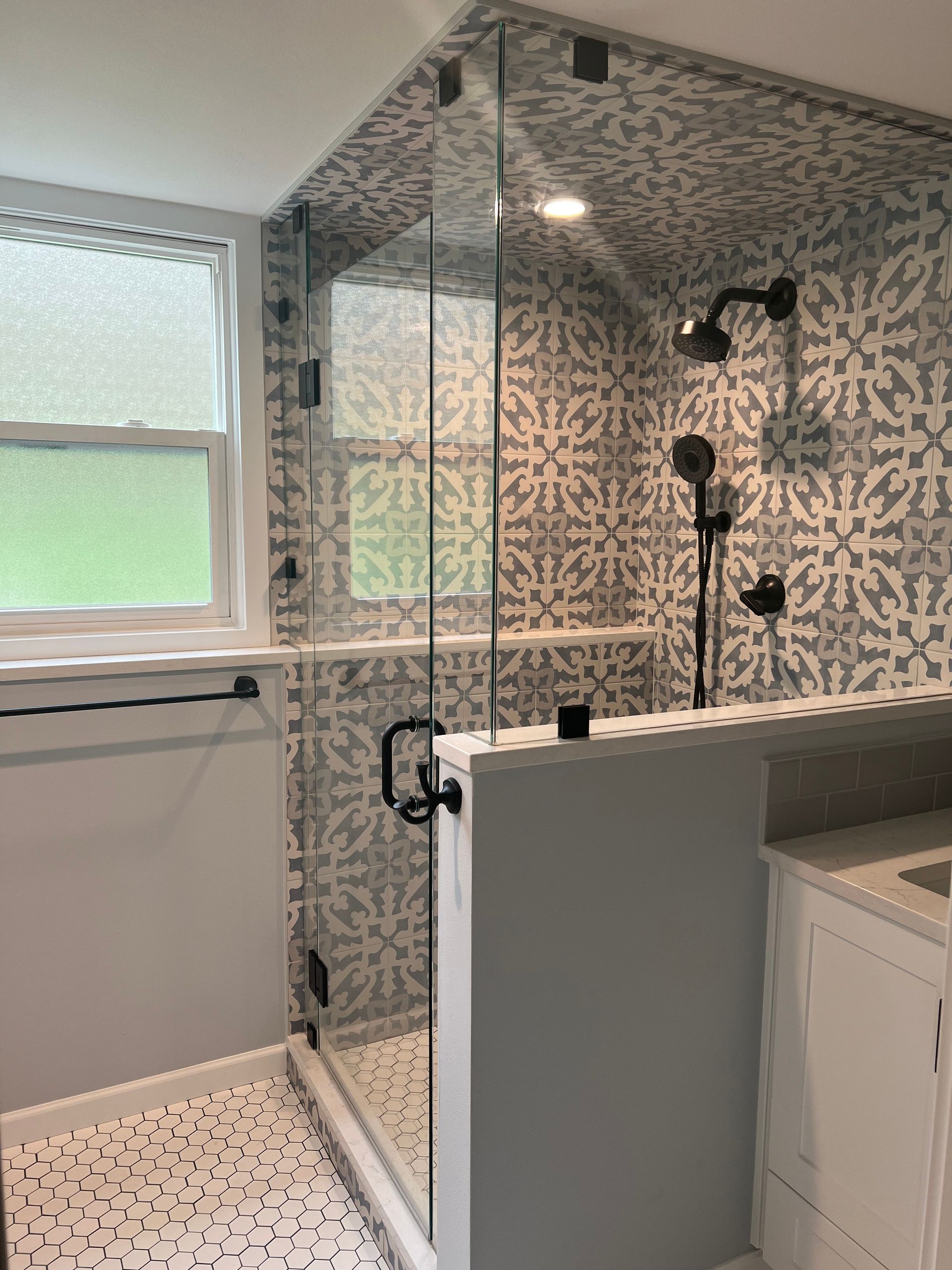 A bathroom with a walk in shower and a window.