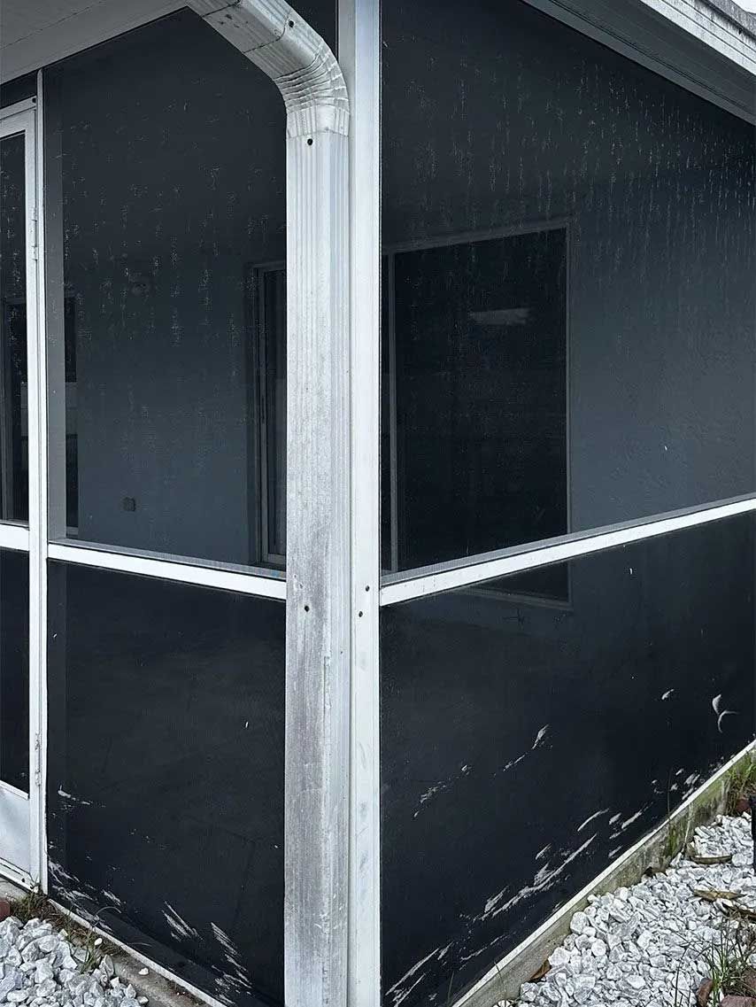 Screened porch with dark walls, white trim, and a gutter, raining.