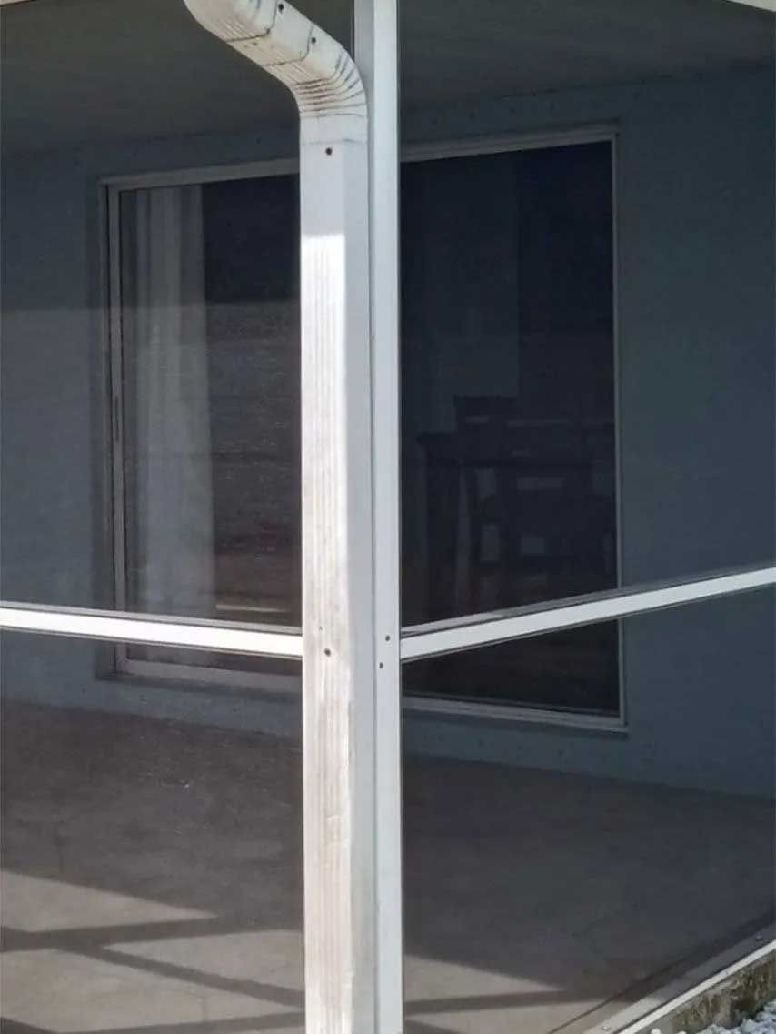 White gutter and support column, against a blue wall, and sliding glass door.
