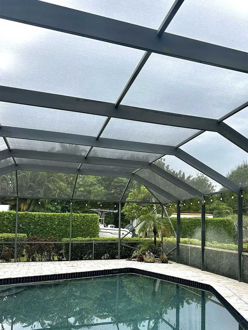 Pool enclosed by a dark gray screened patio with a view of greenery.