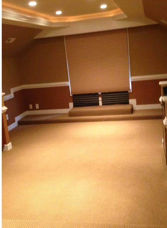 Beige carpeted room with tan walls, brown window shade, and elevated platform.