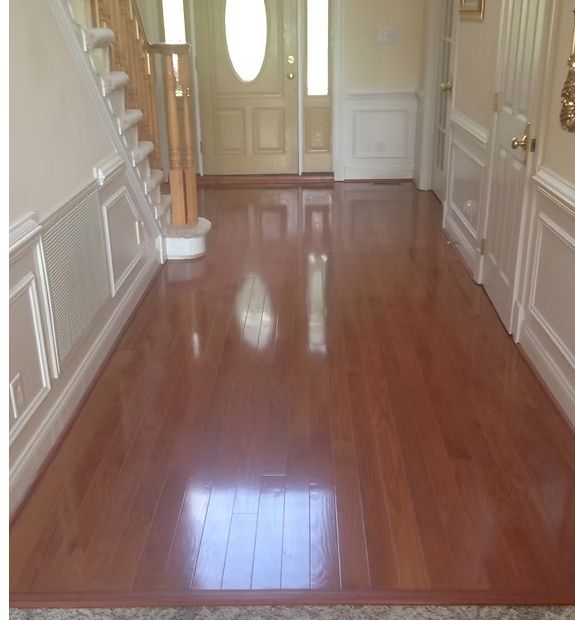 Polished wood floor in a brightly lit entryway, leading to a front door and stairs.