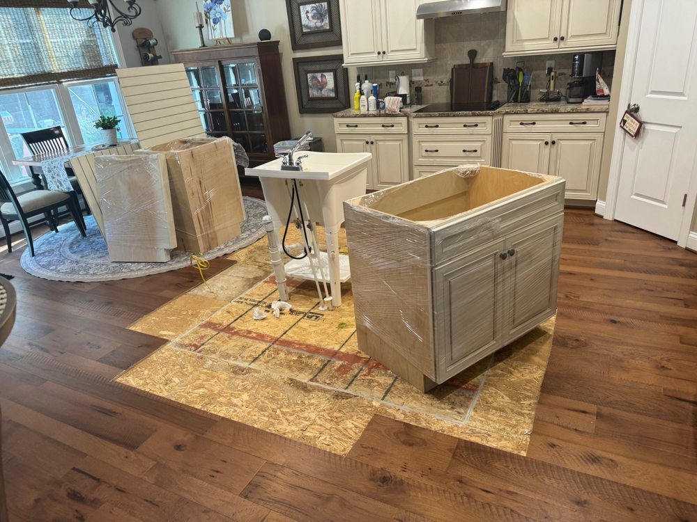 Kitchen cabinets being installed, with flooring covered by protective panels.