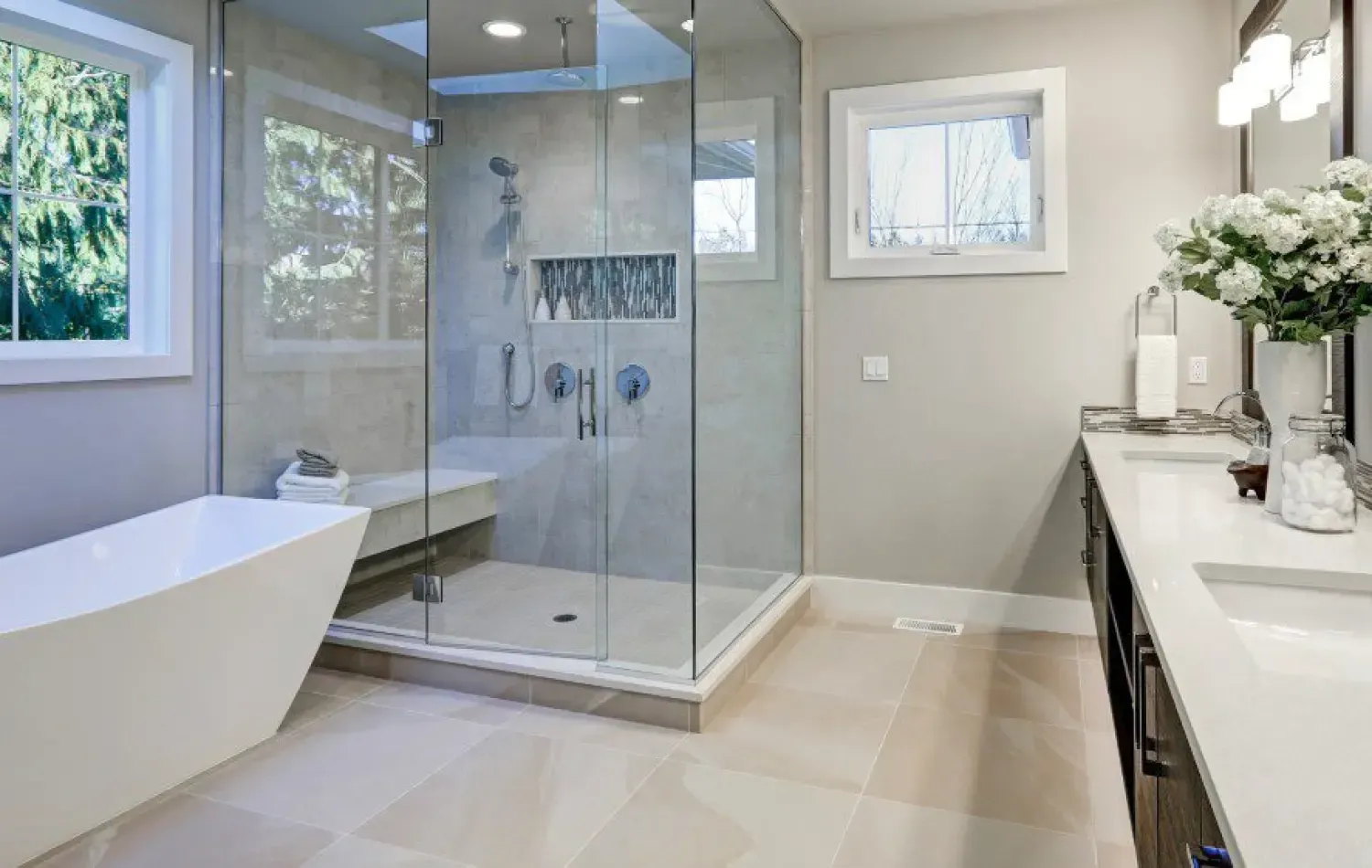 Modern bathroom with glass shower, soaking tub, double vanity, and windows.