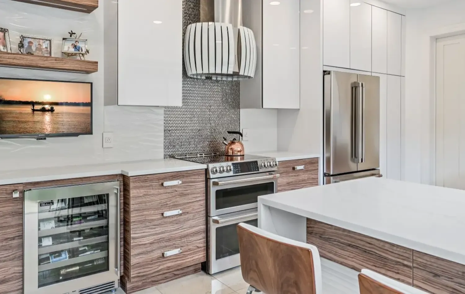 Modern kitchen with white and wood cabinetry, stainless steel appliances, and a TV.