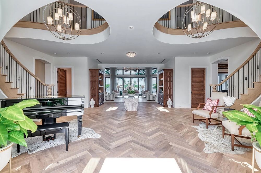 Elegant home interior with grand staircase, piano, and light wood floors.