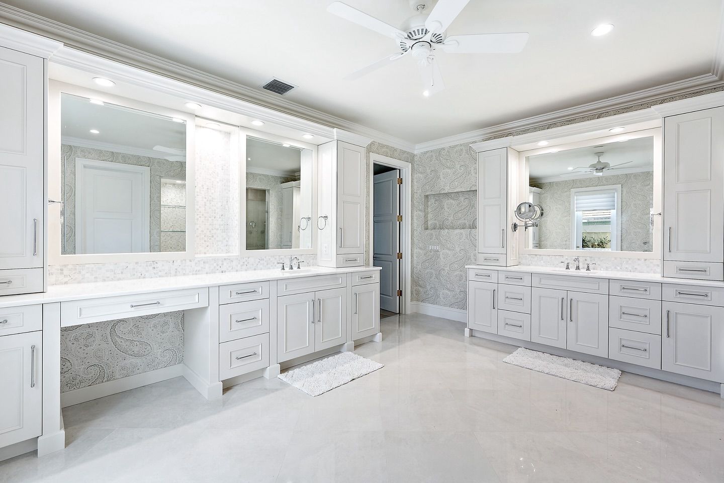 Bright white luxury bathroom with two vanities, large mirrors, and decorative molding.
