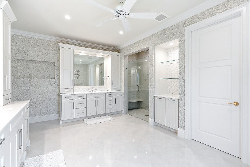 Bright white bathroom with marble tile accents, including a vanity, shower, and door.
