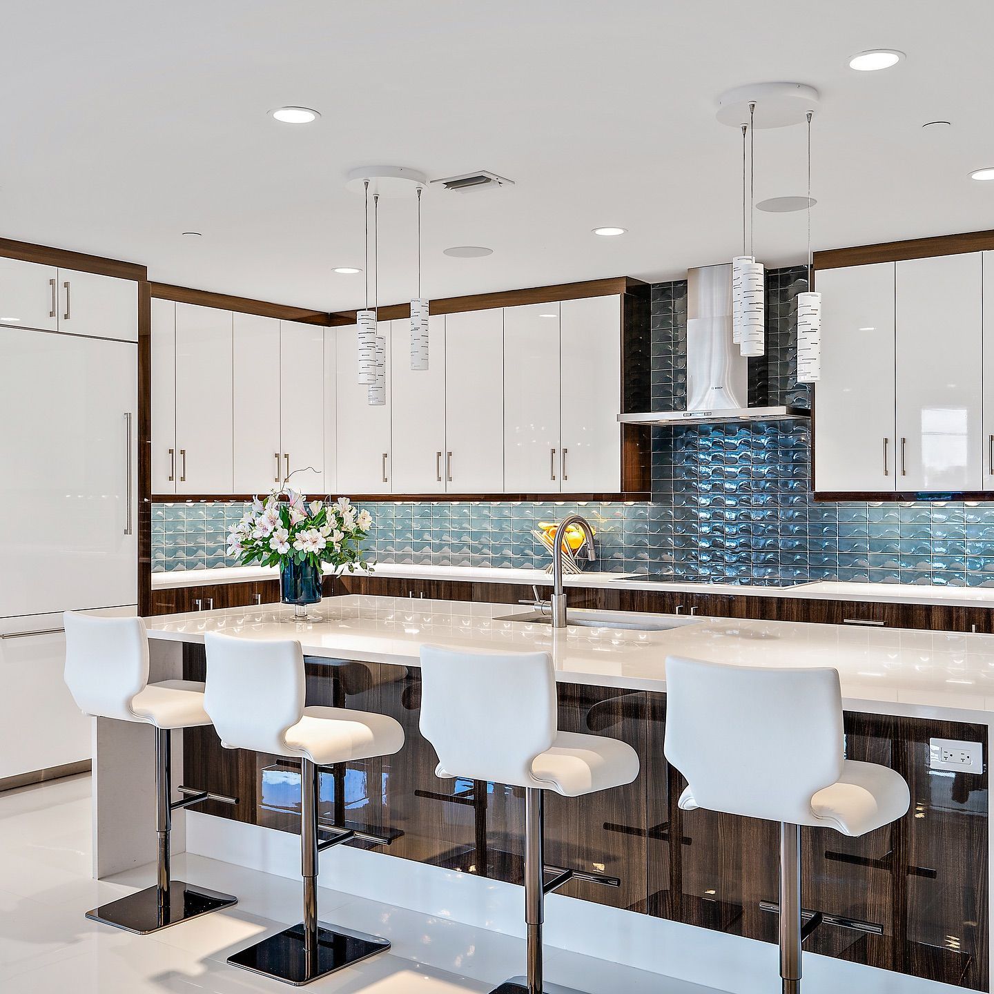 Modern kitchen with white cabinets, dark wood trim, blue tile backsplash, and white bar stools.