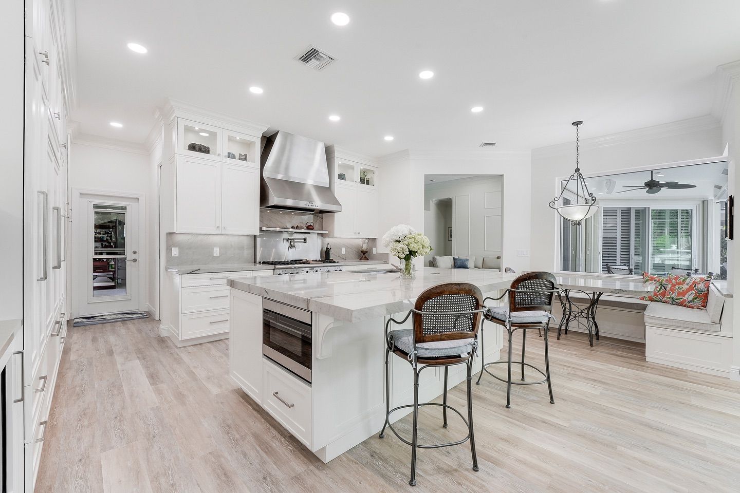 Bright white kitchen with island, stainless steel appliances, and breakfast nook.