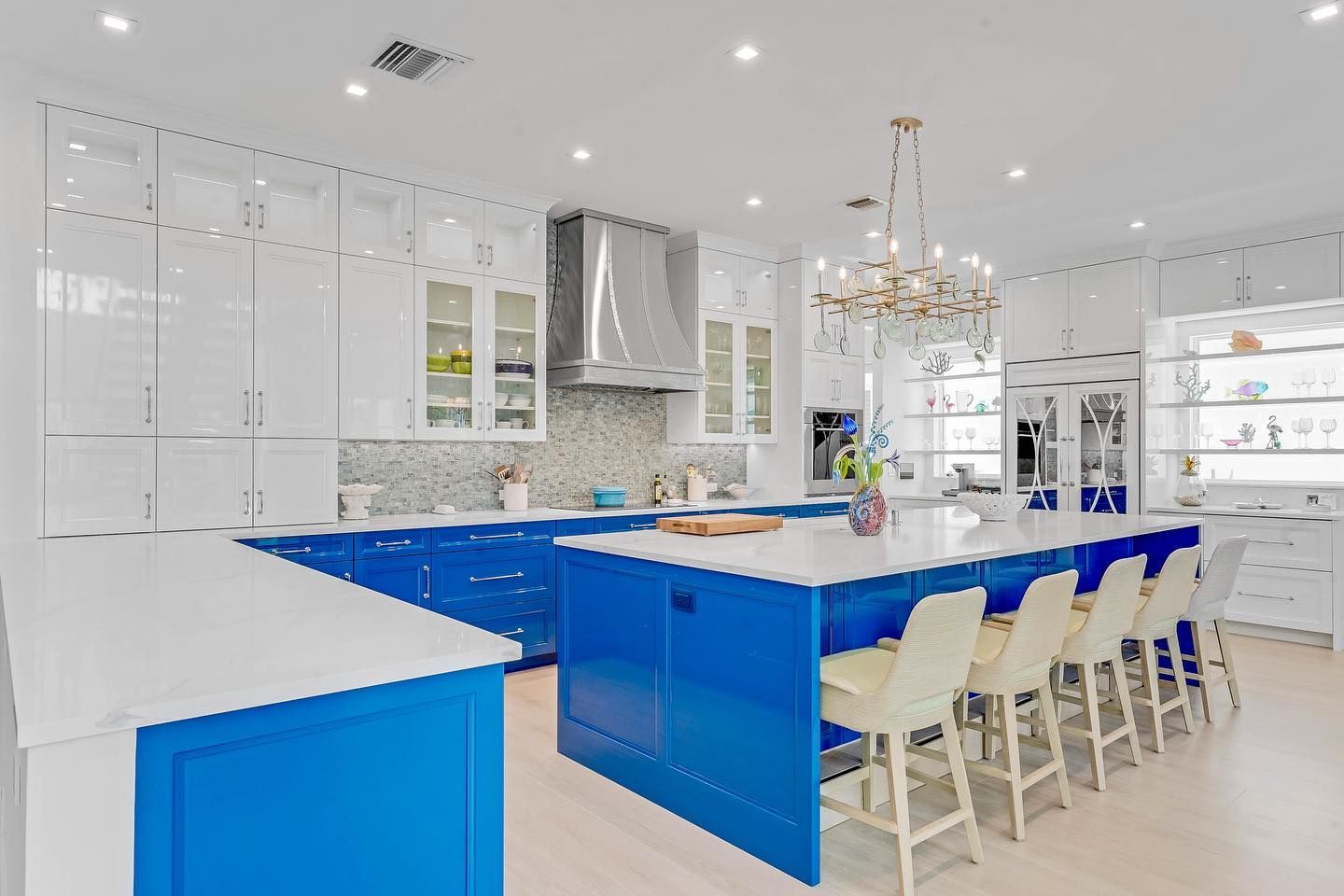 Bright blue and white kitchen with island, cabinets, and chairs.