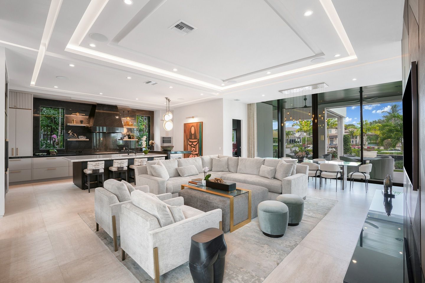 Modern living room with open layout, white sectional sofa, and floor-to-ceiling windows.
