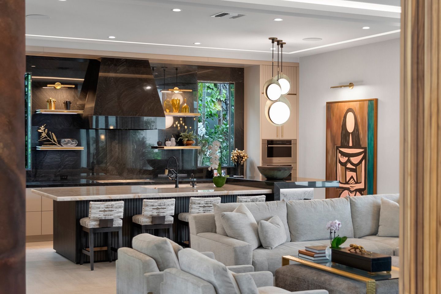 Modern kitchen and living room with dark cabinetry, light-colored sofa, and artwork.