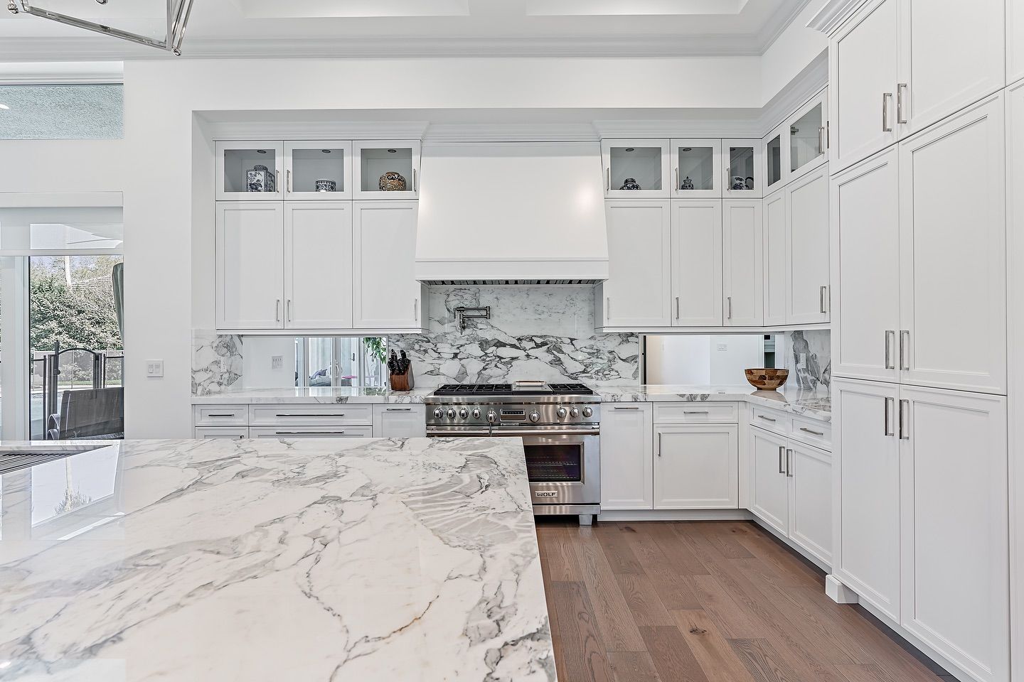 White kitchen with marble countertops, cabinets, and stainless steel appliances.