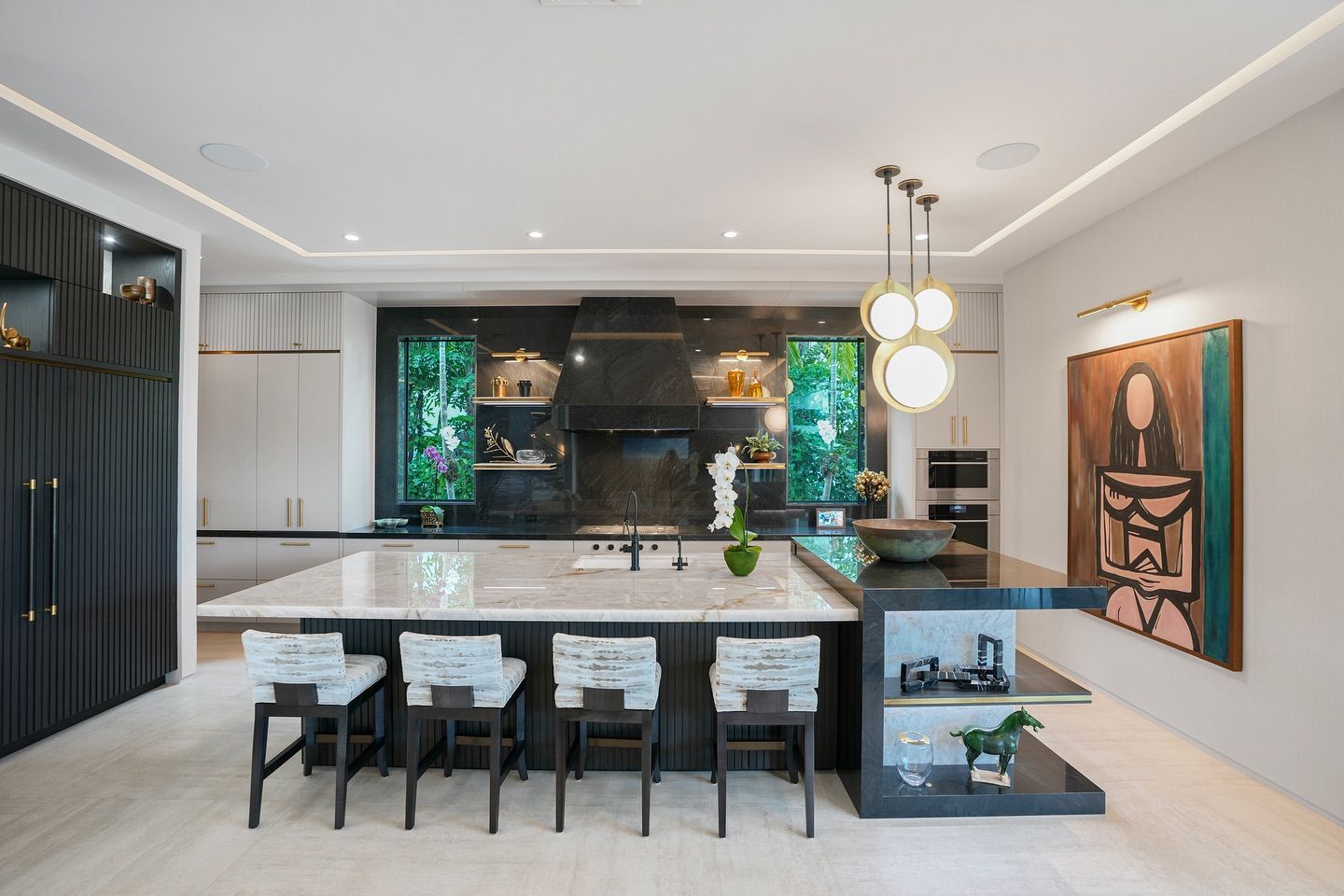 Modern kitchen with large island, seating, dark cabinets, and artwork.
