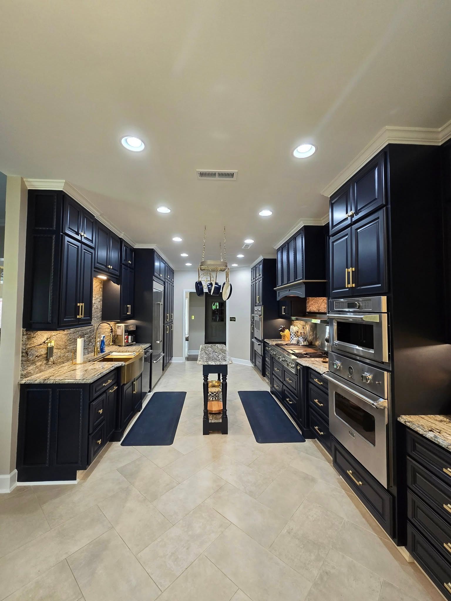 A kitchen with black cabinets , granite counter tops , and stainless steel appliances.