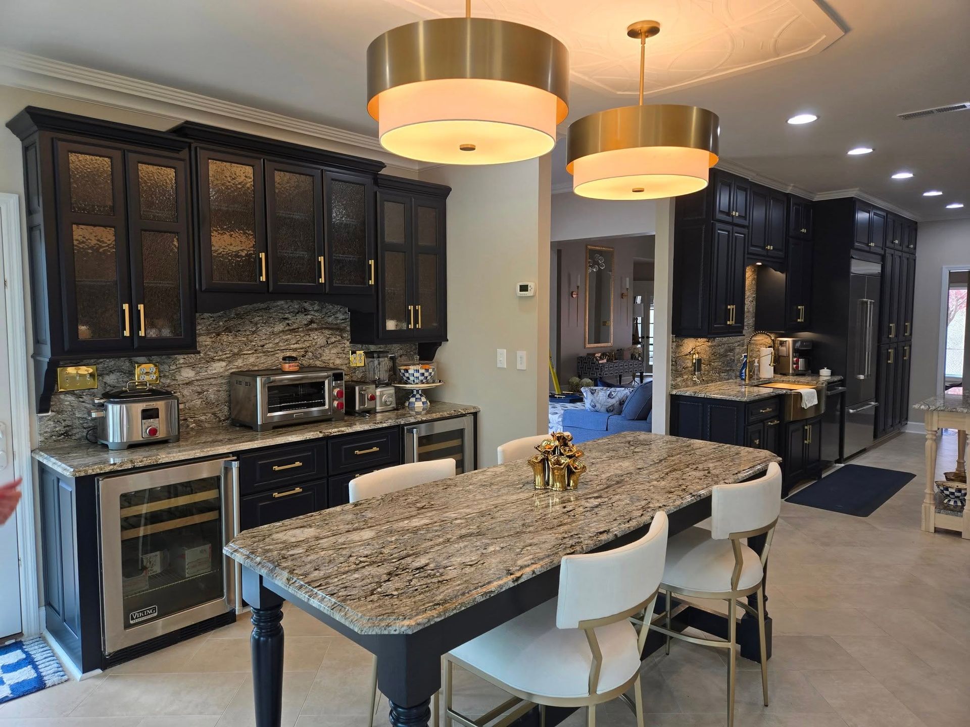 A kitchen with granite counter tops , black cabinets and stainless steel appliances.