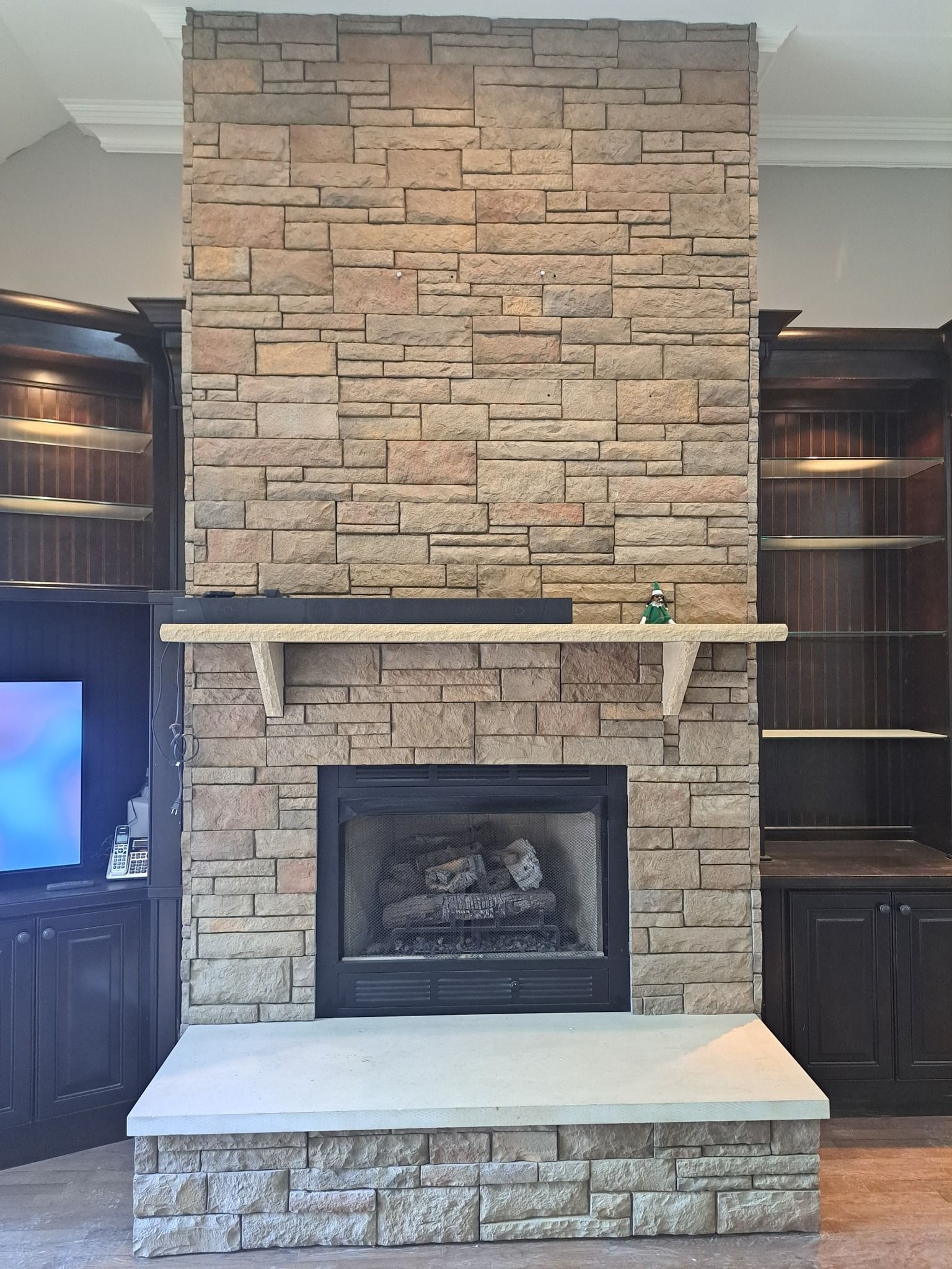 A brick fireplace with a shelf above it in a living room.