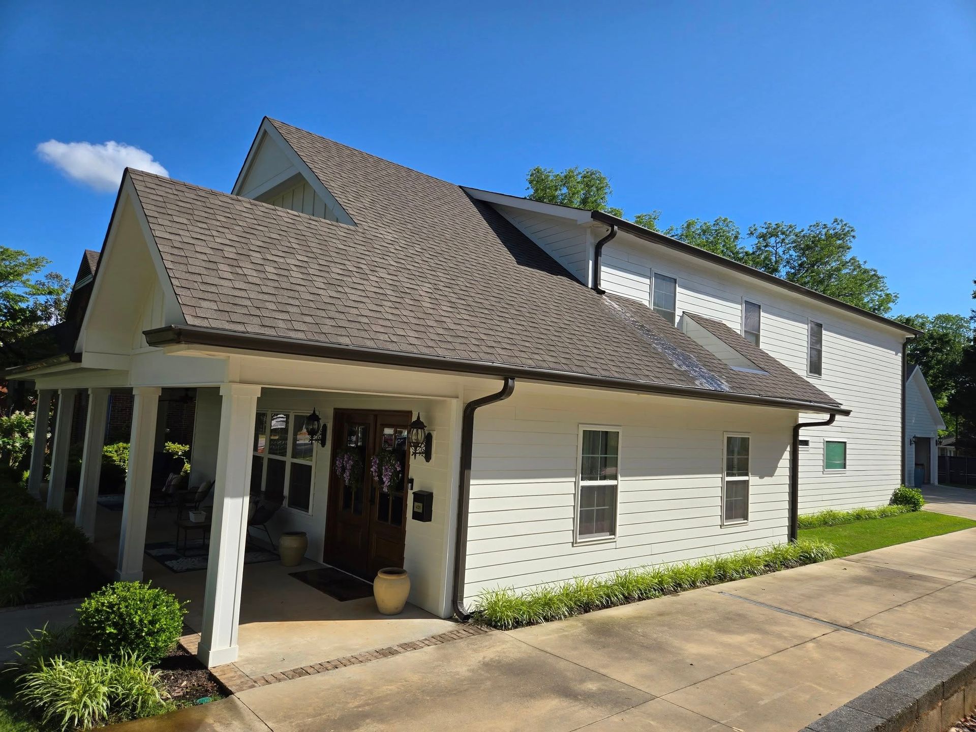 A white house with a brown roof and a porch
