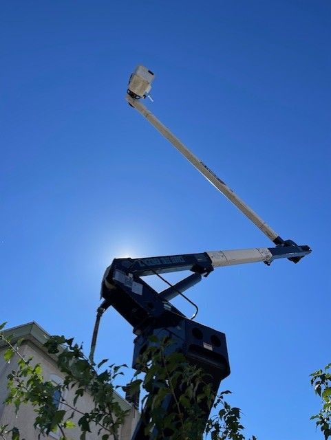Blue sky with a crane extending upwards. Sun shines behind the arm.