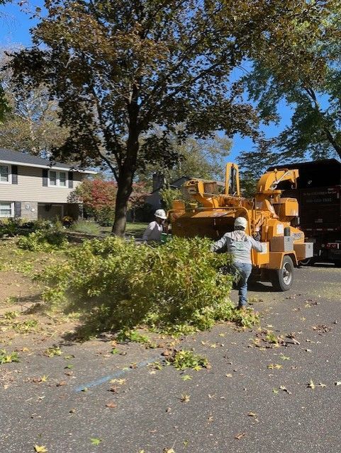 Two workers feeding branches into a wood chipper in a residential area.