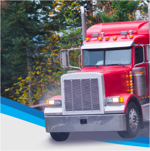 Red semi-truck driving on a road with trees in the background