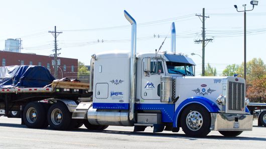 White-and-blue semi truck parked outdoors in a lot, side view.