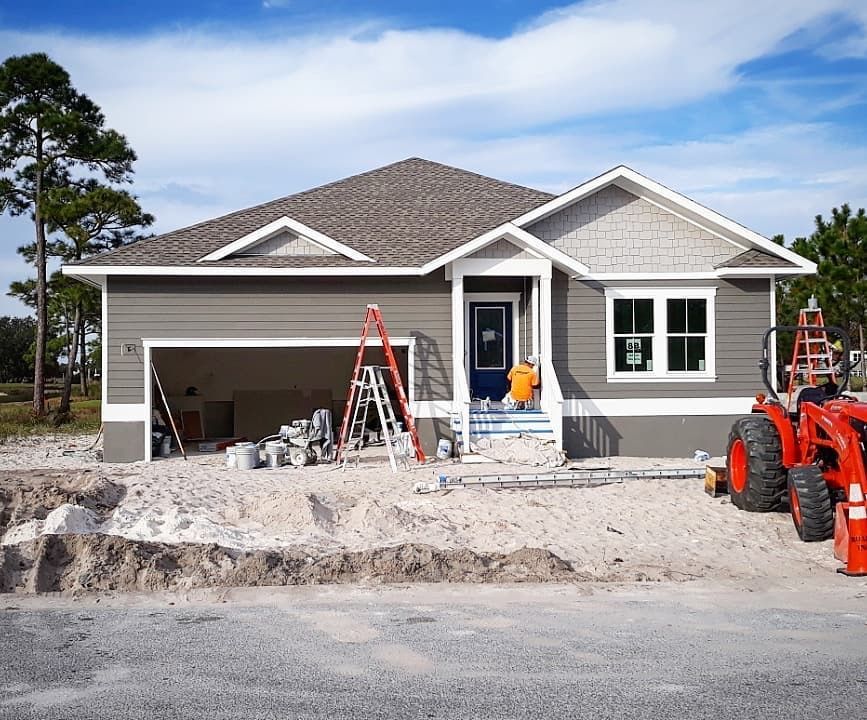 a house is being built and a tractor is parked in front of it .