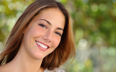A young woman with long brown hair is smiling for the camera.