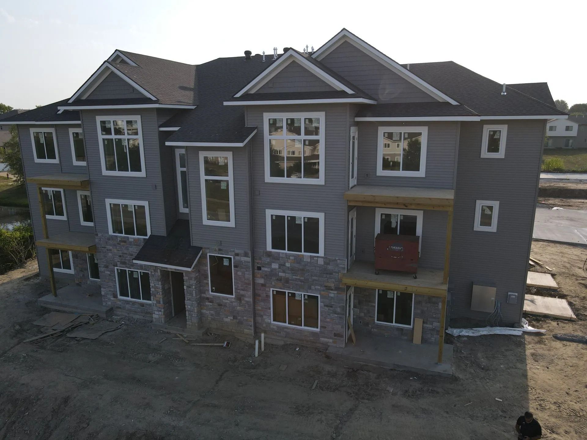 Three-story gray house under construction with white-trim windows and unfinished ground-level exterior