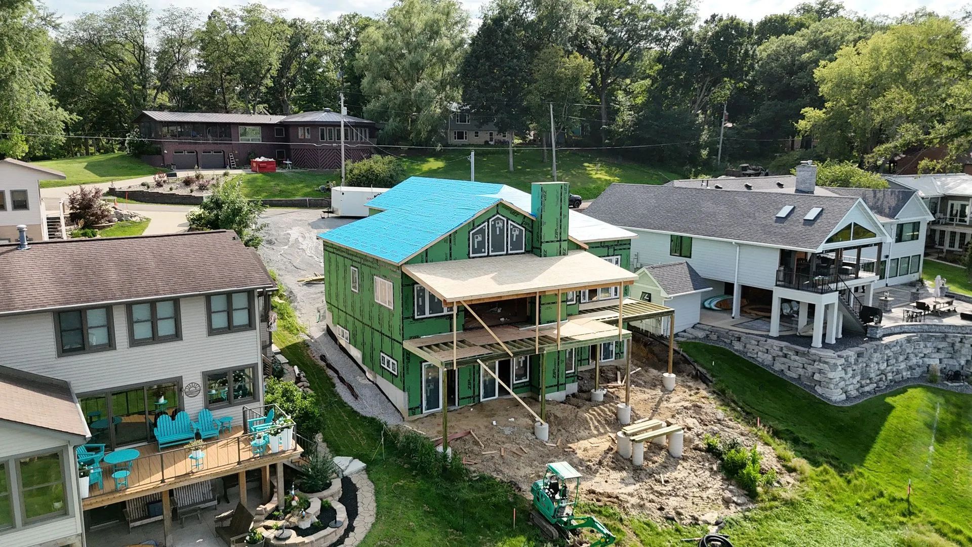 Aerial view of damaged houses in a green neighborhood, with debris scattered around a home under repair.