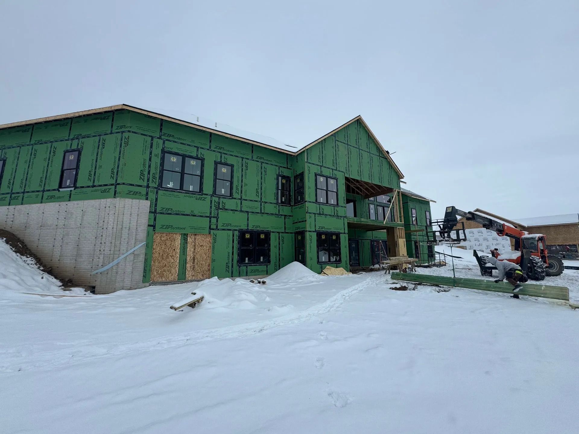 Green house under construction in a snowy landscape with scaffolding and workers nearby