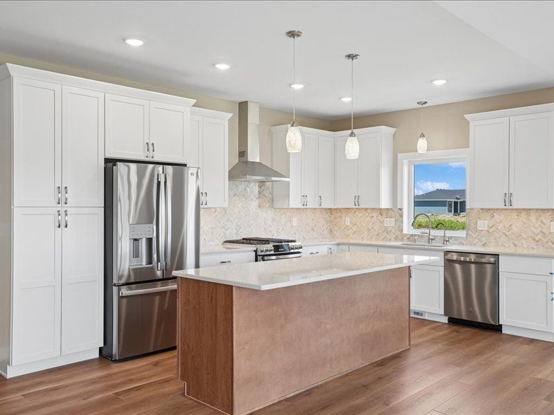 Bright modern kitchen with white cabinets, stainless appliances, and a large wood island
