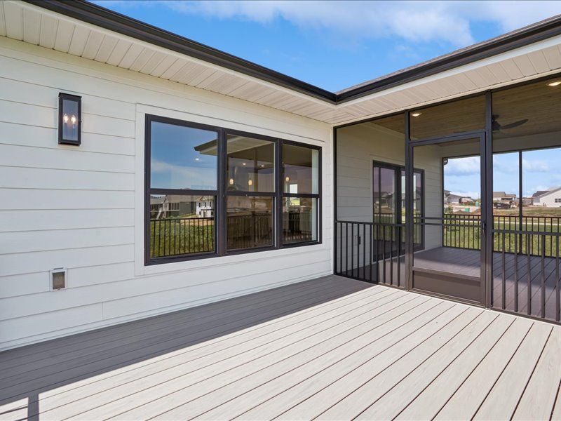 Modern patio with white siding, black-framed windows, and gray decking beside a covered outdoor area
