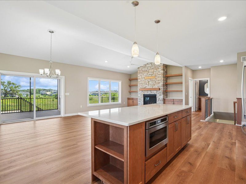 Spacious modern kitchen and living area with wood floors, island, fireplace, and large windows