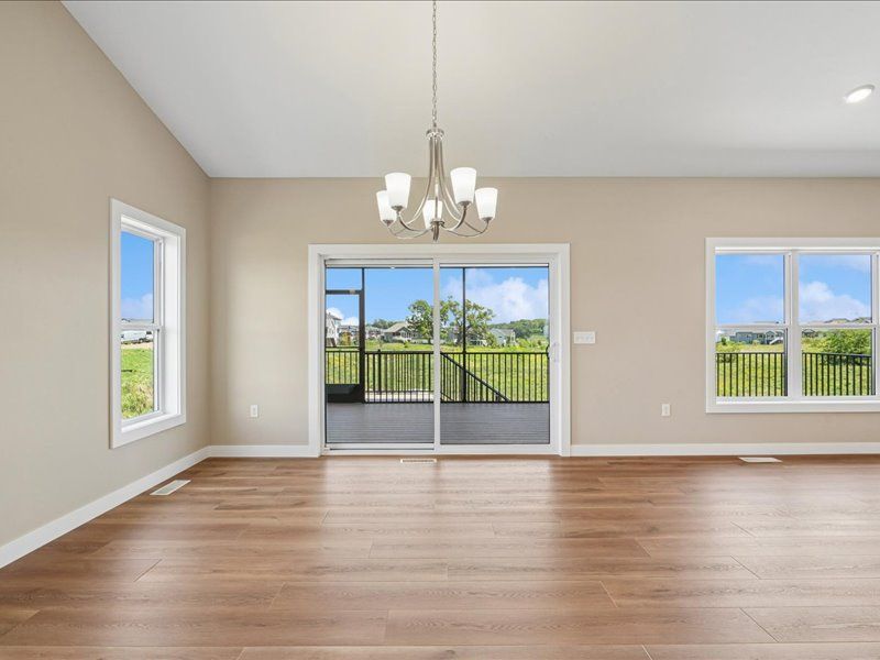 Empty living room with wood floors, beige walls, and sliding glass doors to a balcony view.