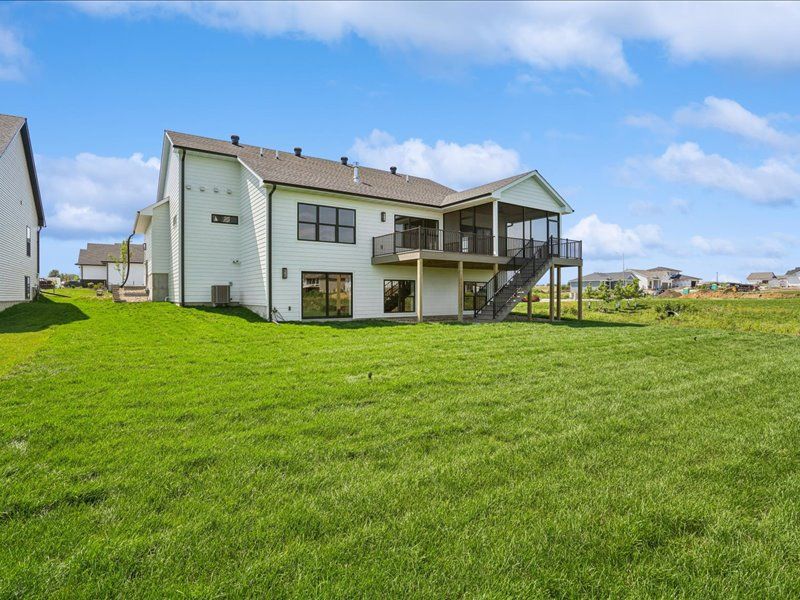 Suburban house with a large green lawn under a blue sky