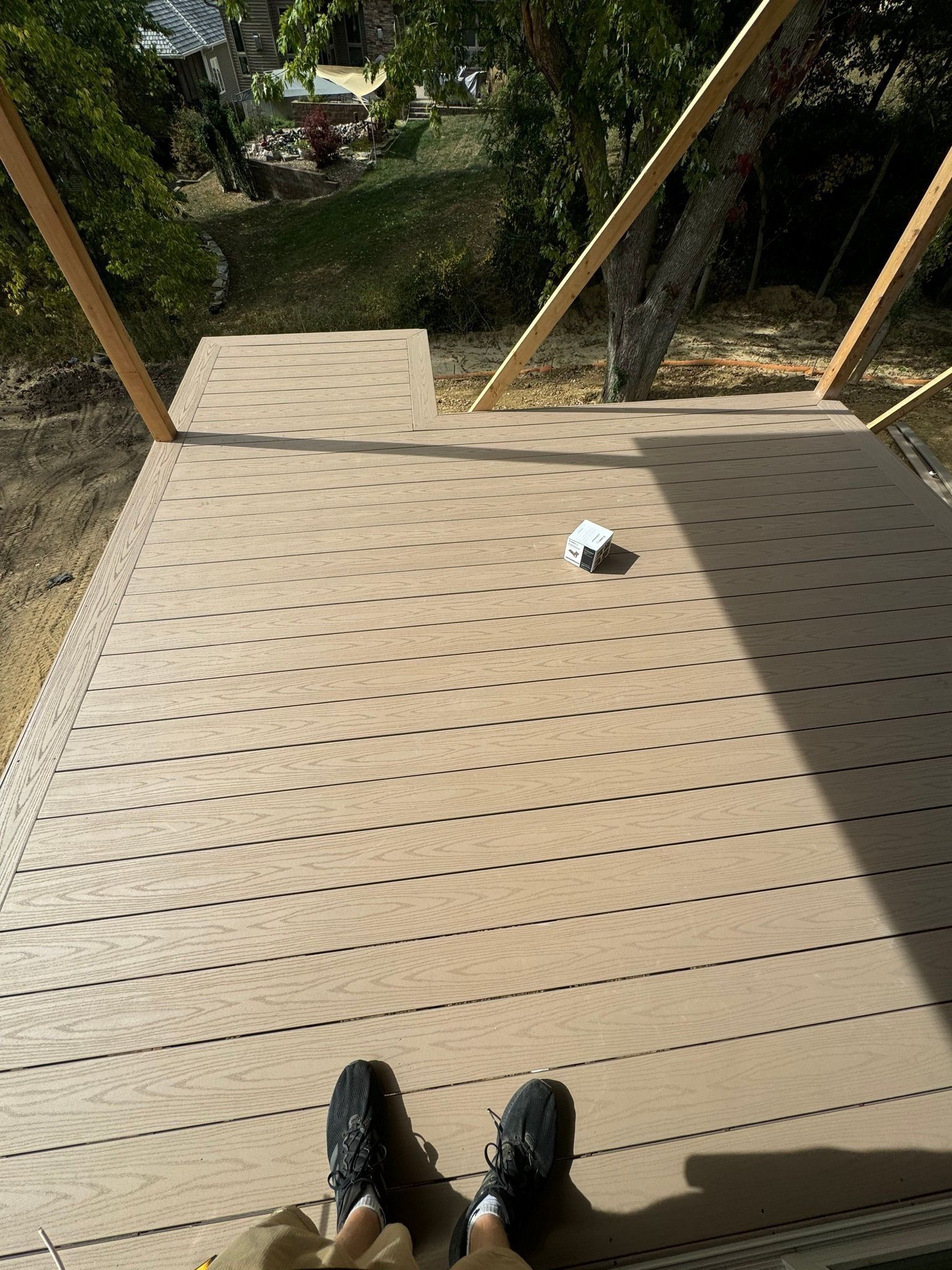 A first-person view looking down at a tan, perforated deck surface with a small white object resting on it.