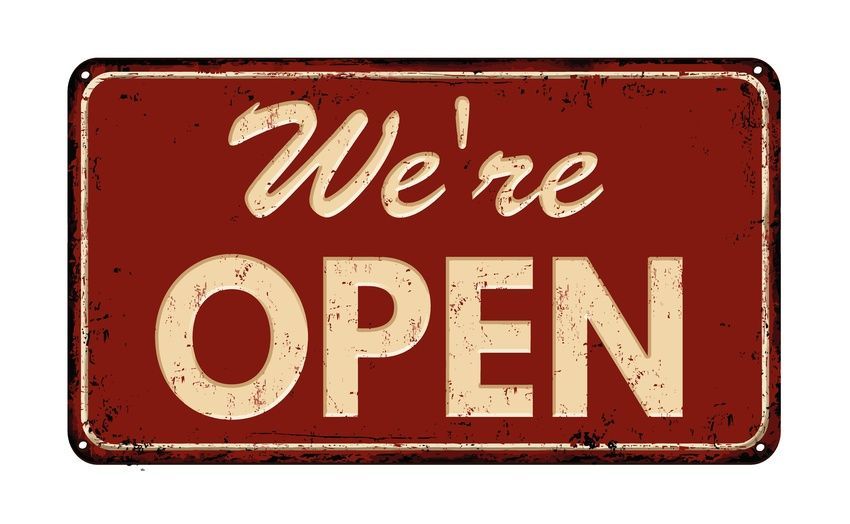 Vintage red sign reading “We’re OPEN” in cream lettering