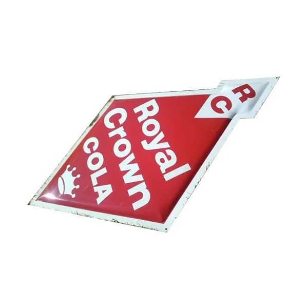 Tilted red Royal Crown Cola sign with white lettering and a small logo at the corner