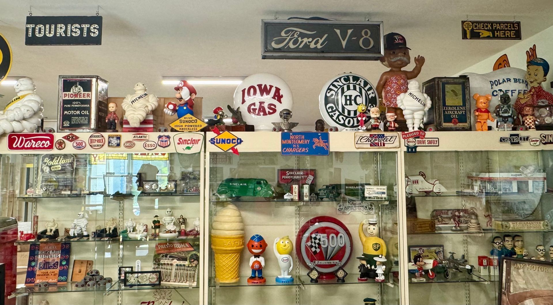 Vintage collectibles displayed on glass shelves in a shop, with signs, toys, and memorabilia.