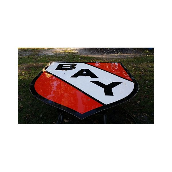 Red and white BAY shield sign lying on grass outdoors