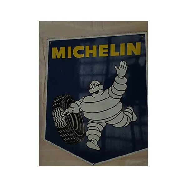 Blue Michelin sign with yellow text and the Bibendum mascot waving beside a tire.