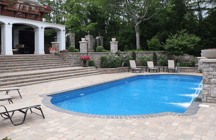 A view of a pool with deck and furnitures