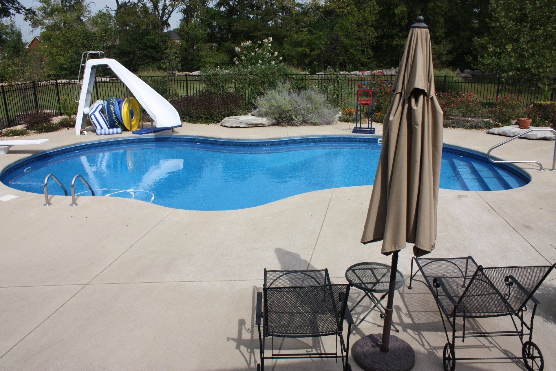 A pool with outside furniture and slide