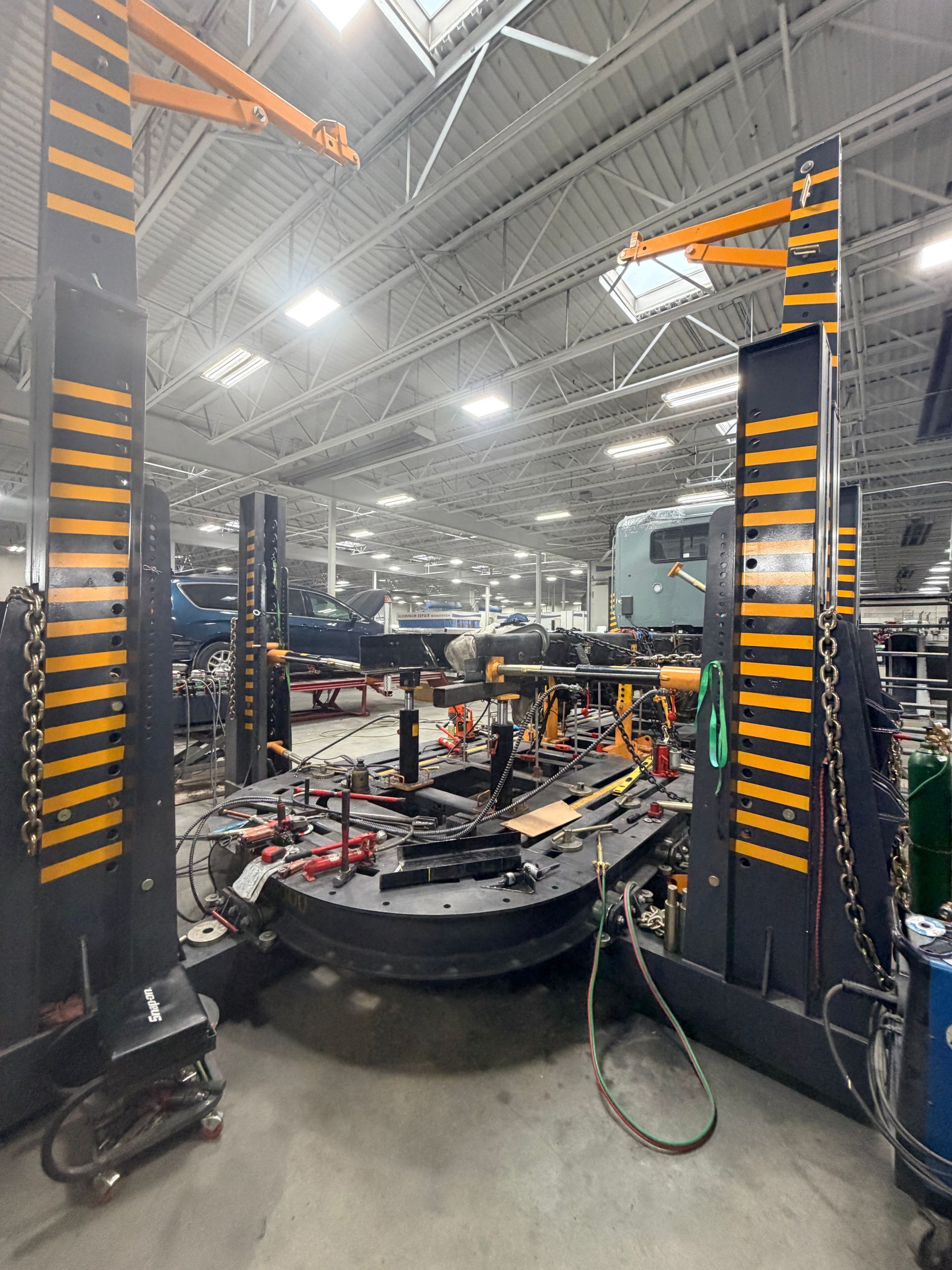 Two heavy-duty industrial lift columns with black and yellow caution markings stand in a large warehouse.